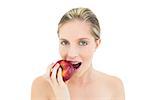 Beautiful fresh blonde woman eating a red apple on white background