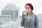 Relaxed casual blonde drinking coffee outdoors on urban background