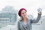 Cheerful pretty blonde taking a self picture outdoors on urban background