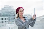 Cheerful pretty blonde holding tablet outdoors on urban background