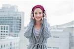 Cheerful pretty blonde listening to music outdoors on urban background