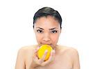 Calm young dark haired model smelling an orange on white background