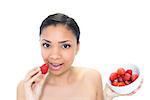 Relaxed young dark haired model eating strawberries on white background
