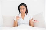 Anxious young dark haired model taking medication in bright bedroom