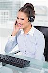 Happy businesswoman using headset in bright office