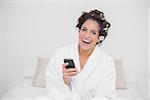 Laughing natural brunette holding smartphone in bedroom