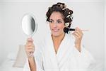 Content natural brunette using brush and mirror in bedroom