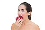 Smiling bare brunette eating red apple on white background
