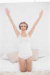Woman raising her arms while listening to music and laughing into the camera