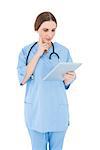 Thinking female doctor holding a tablet on white background