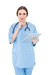 Thinking female doctor holding a tablet and looking into the camera on white background