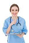 Thinking female doctor keeping a clipboard smiling into the camera on white background