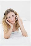 Pretty peaceful blonde lying on bed phoning in bright bedroom