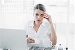Unhappy businesswoman working sitting at her desk looking at camera