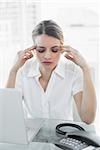 Beautiful suffering businesswoman having headache sitting at her desk with eyes closed