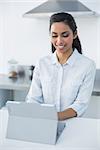 Cute woman using her tablet standing in bright kitchen at home