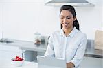 Beautiful woman working on her tablet standing in her kitchen at home