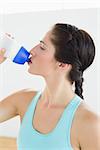 Close up of a fit young woman drinking water at the gym after working out