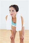 Tired young woman with towel around neck at fitness studio