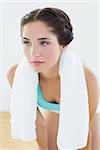 Close up of a tired young woman with towel around neck at fitness studio