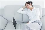 Well dressed young woman resting on sofa while using laptop at home