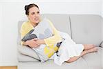 Thoughtful young woman relaxing on sofa at home as she looks away