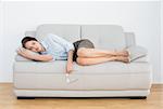 Full length of a well dressed young woman sleeping on sofa at home