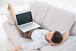 High angle view of a young woman with laptop lying on sofa at home