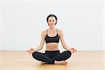 Toned content brunette sitting in lotus pose at fitness studio