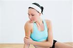 Thoughtful toned woman sitting in fitness studio