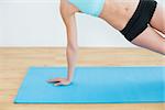 Close up of a slim young woman doing the side plank yoga pose in fitness studio