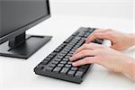 Close up of hands typing on a keyboard in an office