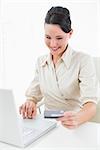 Smiling young businesswoman doing online shopping through laptop and credit card