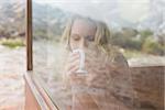 View of a young woman drinking coffee through cabin window