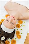 Overhead of a beautiful young woman with eyes closed and flowers in beauty salon