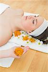 Overhead view of a beautiful young woman with eyes closed and flowers in beauty salon