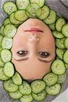 Close up portrait of a young beautiful woman with facial mask of cucumber slices on her face at spa salon