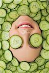 Close up of a young beautiful woman with facial mask of cucumber slices on her face at spa salon