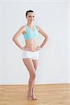 Portrait of a smiling toned young woman with hands on hips in fitness studio