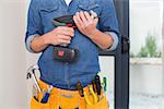 Close up mid section of a handyman with drill and toolbelt