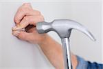 Extreme Close up of a handyman hammering nail in wall