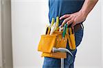 Side view mid section of a handyman with toolbelt around his waist