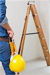 Mid section of a handyman with toolbelt around his waist and hard hat