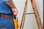 Mid section of a handyman with toolbelt around his waist