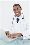 Portrait of a smiling male doctor using laptop at medical office