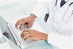 Close up of doctor's hands using laptop at medical office