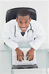 Overhead portrait of a smiling male doctor using laptop at medical office