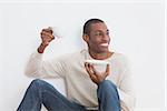 Casual happy Afro young man having tea against the wall