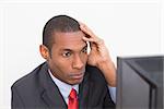 Close up of a serious young Afro businessman looking at computer against white background