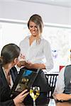 Businesswoman ordering dinner from pretty waitress in a restaurant